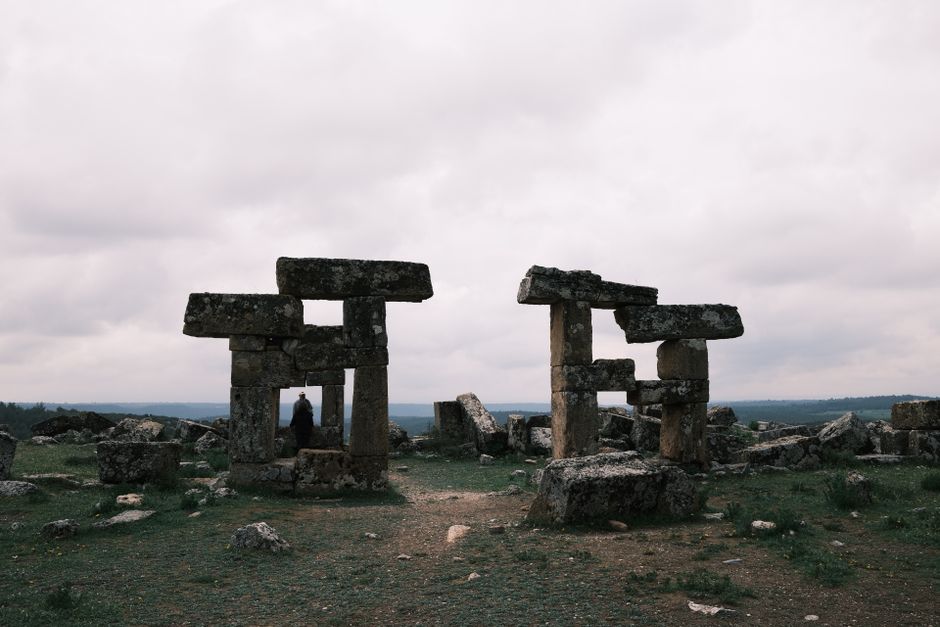 Explore ancient stone ruins under a dramatic cloudy sky, capturing a sense of history.